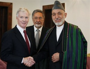 In this image made available from the Afghanistan Presidential Palace, Afghan President Hamid Karzai, center, shakes hand with new U.S. ambassador to Afghanistan Ryan Crocker at the Presidential Palace in Kabul, Afghanistan on Monday, July 25, 2011. The new U.S. ambassador to Afghanistan said Monday that the United States is not rushing to leave the country and cautioned that what happens in the months ahead will have far-reaching effects across the globe. (AP Photo/Presidential Palace)